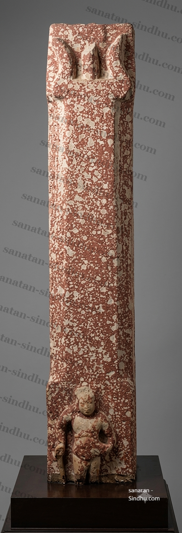 Carved red sandstone Śiva pillar (mukhaliṅga) from Mathura, dated 380 CE, with a standing figure at its base.